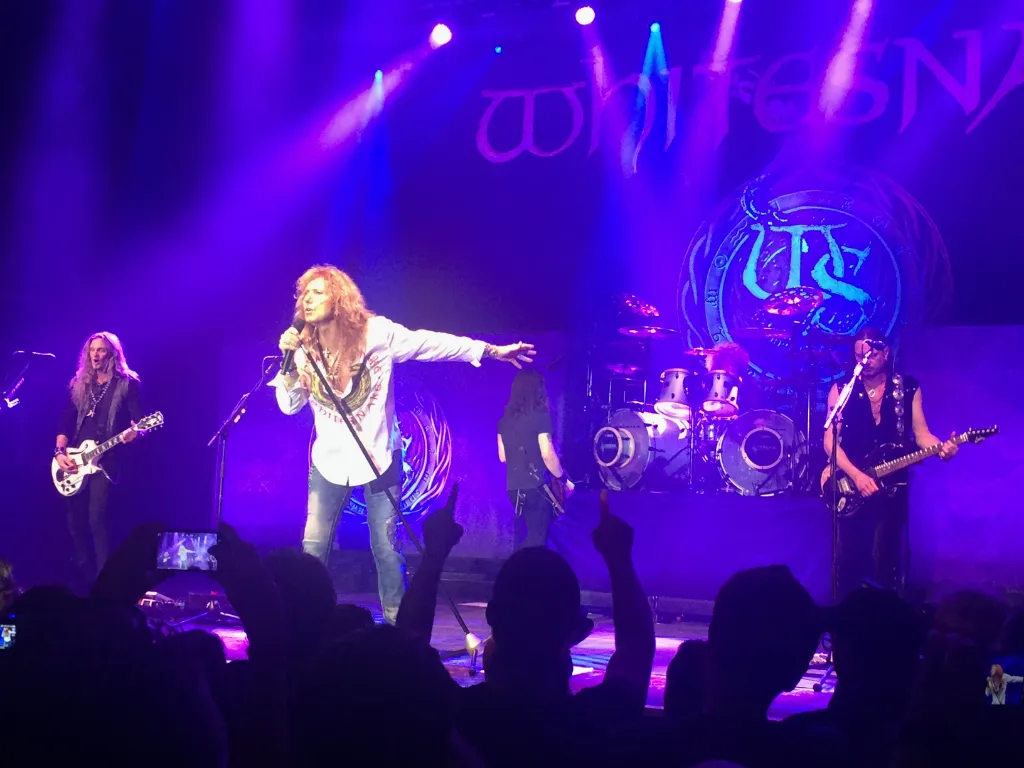 David Coverdale singt mit ausgestrecktem Arm vor der Band und dem Whitesnake-Logo auf der Bühne im Z7.