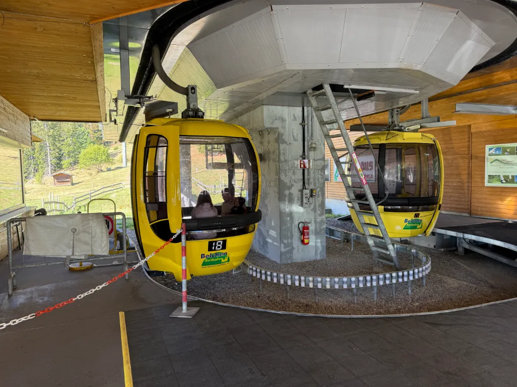 Gelbe Gondeln der Belchen-Seilbahn in der Bergstation, eine davon mit Fahrgästen besetzt